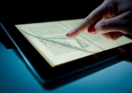 Une main fait tourner les pages d'un ebook sur une tablette numérique